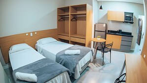Una habitación de hotel con dos camas, una kitchenette y un pequeño comedor.