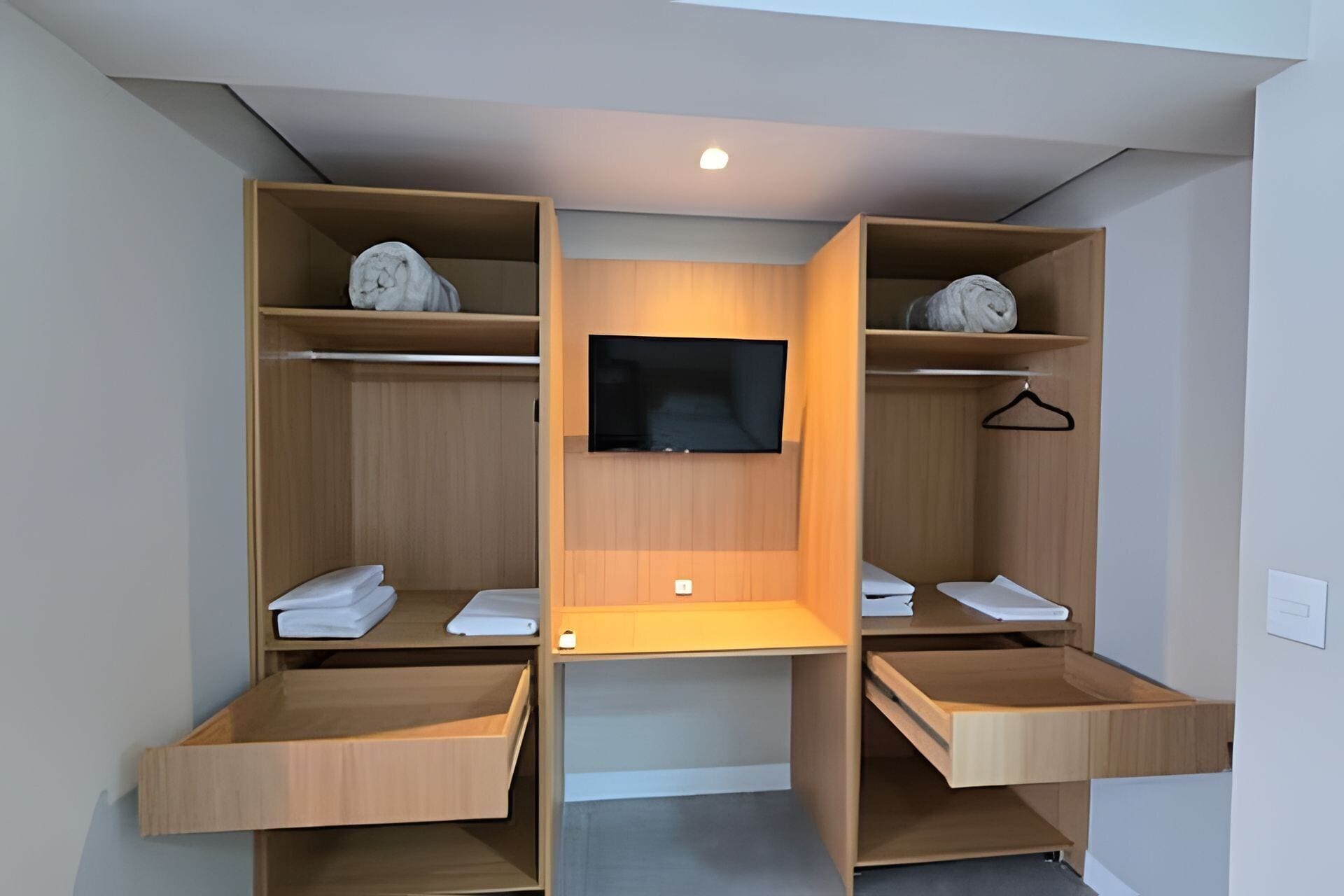 Un placard moderne avec des étagères en bois, un téléviseur à écran plat et un espace bureau.
