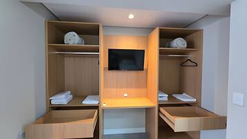 Un placard moderne avec des étagères en bois, un téléviseur à écran plat et un espace bureau.
