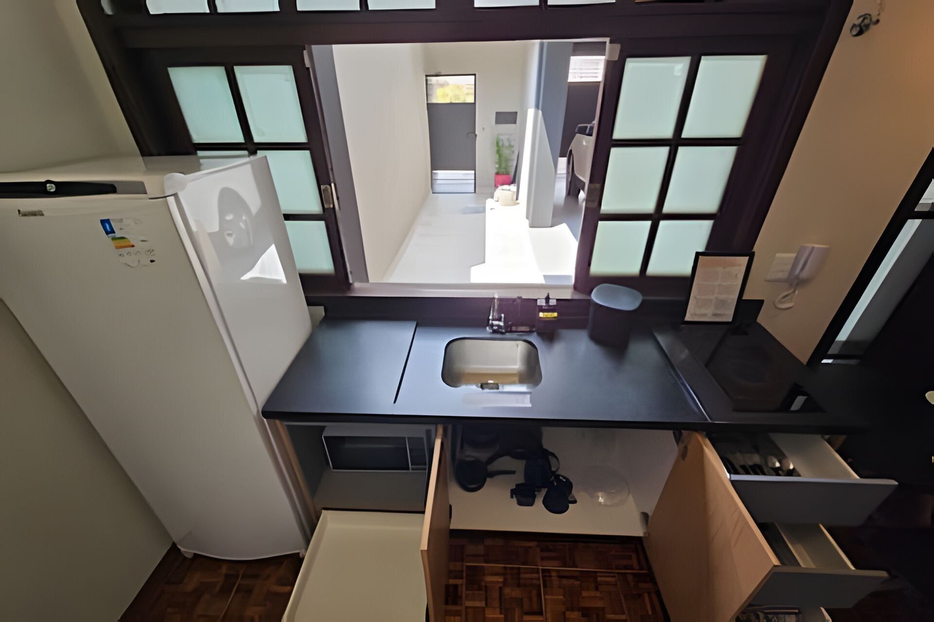 A compact kitchen with a refrigerator, sink, and a view through a window.