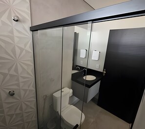 A modern bathroom with a glass partition, a toilet, a sink, and a mirror.
