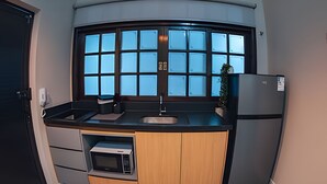 Cocina compacta con microondas, fregadero y refrigerador, que cuenta con un ventanal grande y una encimera curva.