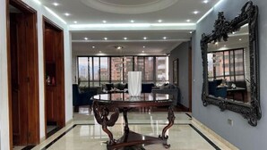 Une pièce spacieuse avec une table ronde, de grandes fenêtres et un miroir au mur.