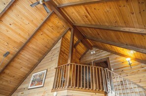 A wooden interior with a staircase, wooden beams, and a light fixture. - Chalets Gallix (Sept-Îles)
