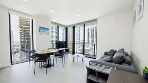A modern apartment with a dining area, a sofa, and large windows offering city views. - 34th Floor Luxurious 1BR - Epic View & Top Location (Miami)