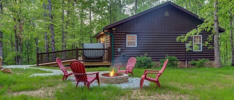 A log cabin with a deck, outdoor seating, and a fire pit.