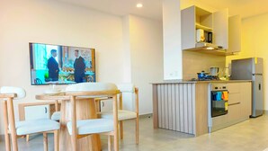 Una cocina moderna con horno empotrado, comedor con mesa redonda y sillas, y televisor de pantalla plana montado en la pared.