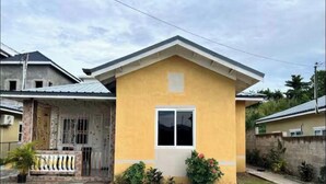 A single-story house with a gabled roof, a small window, and a front porch. - Terrific 2-bedroom house with AC in Montego Bay (Montego Bay)