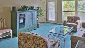 Une pièce spacieuse dotée d’un ventilateur de plafond, d’une grande fenêtre et d’un coin salon avec une table basse.