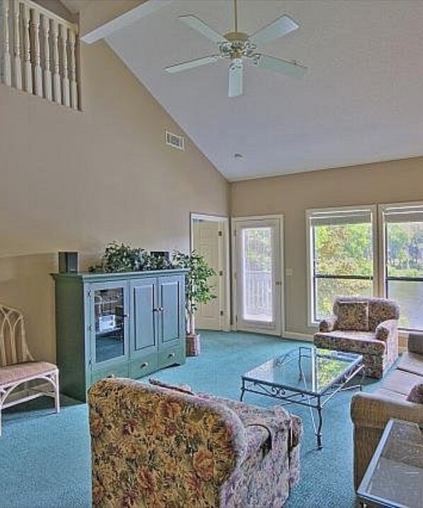 A spacious room with a ceiling fan, a large window, and a seating area with a coffee table.