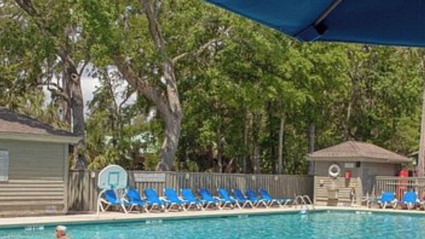 Une piscine avec des chaises longues bleues et une clôture en bois.