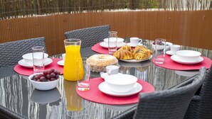 A breakfast table with plates, cups, and a glass of orange juice. - Vilamoura Secret - City center with pool by HD (Vilamoura)