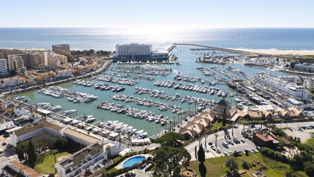 An aerial view of a marina with numerous boats docked, surrounded by buildings and a clear view of the sea. - Vilamoura Secret - City center with pool by HD (Vilamoura)