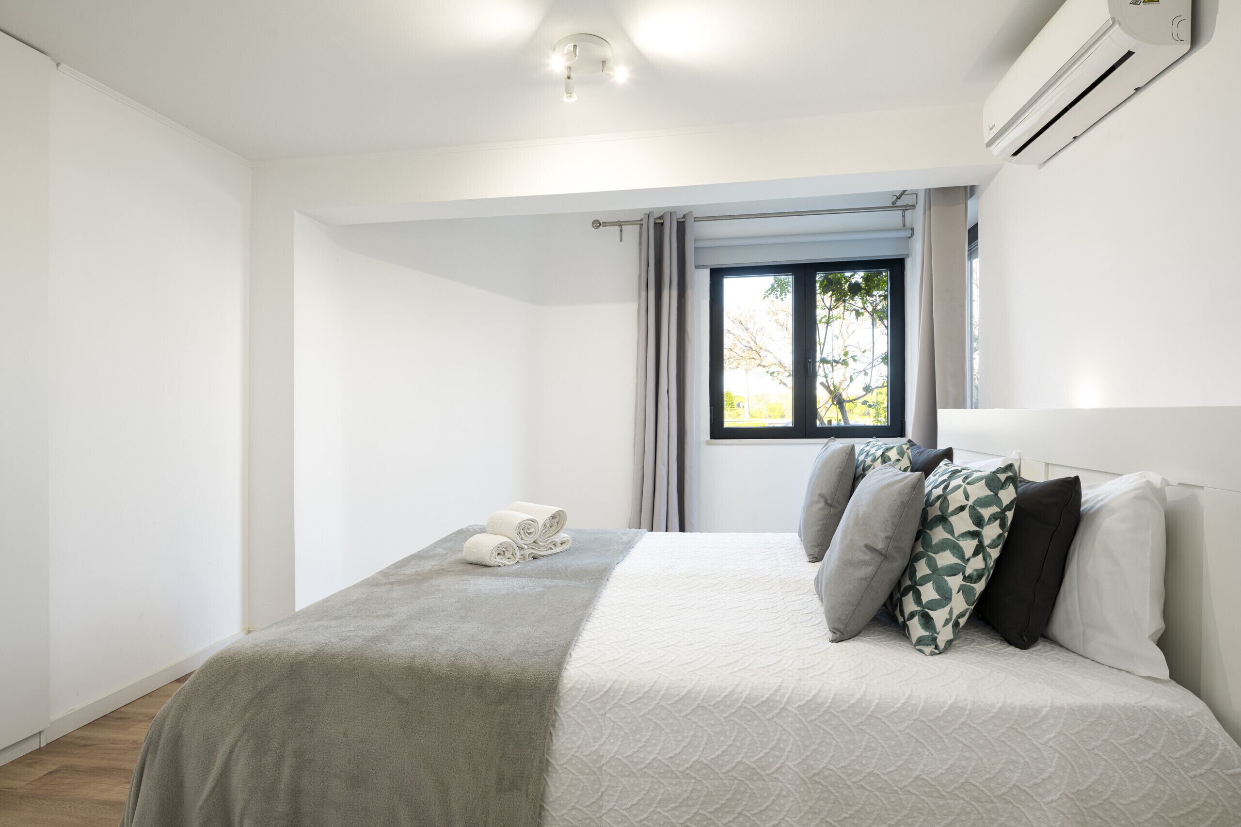 A bedroom with a bed, a window, and an air conditioning unit.