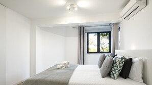 A bedroom with a bed, a window, and an air conditioning unit. - Vilamoura Secret - City center with pool by HD (Vilamoura)