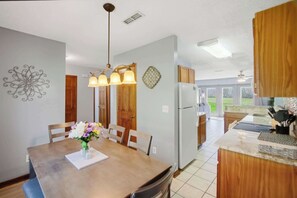 A kitchen with wooden cabinets, a refrigerator, a dining table with chairs, and a pendant light. - Fireplace Retreat・Mtn / Golf Views・Near Downtown (Gatlinburg)
