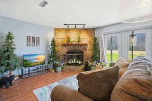 A living room with a stone fireplace, a television, and a couch. - Fireplace Retreat・Mtn / Golf Views・Near Downtown (Gatlinburg)