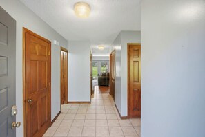 A hallway with wooden doors, a tiled floor, and a ceiling light. - Fireplace Retreat・Mtn / Golf Views・Near Downtown (Gatlinburg)