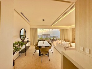 A modern hotel room with a dining area, a sofa, a large mirror, and a view of the city. - Romantic Retreat Soho PV (Puerto Vallarta)