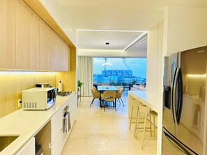 A modern kitchen with a view of a cityscape, a dining area with chairs, and a large refrigerator. - Romantic Retreat Soho PV (Puerto Vallarta)