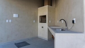 A modern kitchen with a built-in oven, a sink, and a countertop. - Condomínio Triangulo da Embauba  (Porto Seguro)