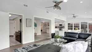 A modern living room with a leather sofa, a coffee table, and a ceiling fan. - 3/2 Heated Pool home Walking Distance to beach (Naples)