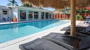 A swimming pool with lounge chairs and a thatched umbrella. - 3/2 Heated Pool home Walking Distance to beach (Naples)