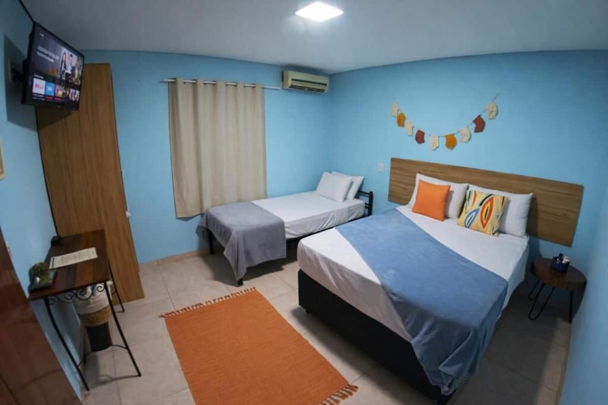 A room with two beds, a TV, a desk, and a curtain.
