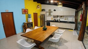 A dining area with a wooden table and white chairs, a kitchen with white cabinets, and a door labeled '5'. - Villa Kanindé Bonito (Bonito)
