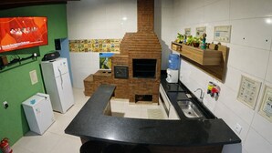 A kitchen with a brick oven, a refrigerator, a sink, and a bar area with stools. - Villa Kanindé Bonito (Bonito)