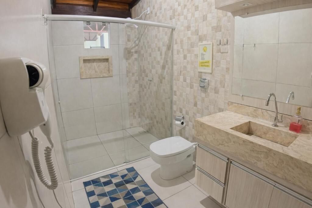 A bathroom with a shower, toilet, sink, and a telephone.