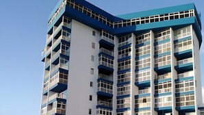 Een meerlaags hotel met een modern ontwerp, voorzien van balkons, een zwembad en een parkeerplaats.