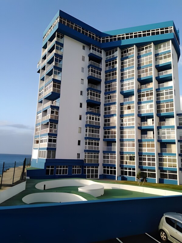 Un hôtel à plusieurs étages, doté d’un design moderne, comprenant des balcons, une piscine et un espace de stationnement.
