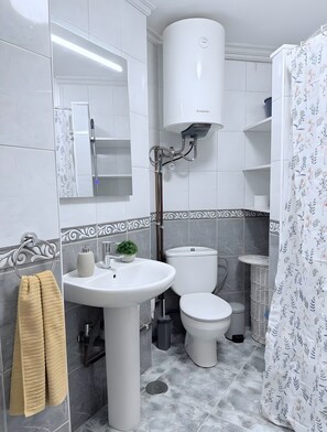 Une salle de bain avec un lavabo blanc, des toilettes et un rideau de douche.