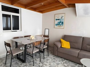 A dining area with a table, chairs, and a sofa. - Sunset Beach Apartment Tenerife (Tacoronte)