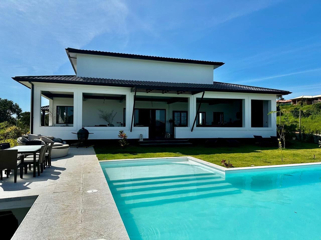 A modern house with a swimming pool, outdoor seating, and a well-maintained lawn.