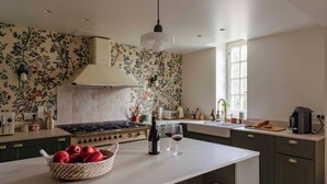 A kitchen with a gas stove, a sink, a window, and a decorative wall. - Manoir de charme en Normandie | piscine chauffée à moins de 2h de Paris. (Chambord)