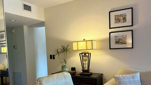 A living room with a sofa, a chair, a lamp, and framed pictures on the wall. - Charming 2-bedroom apartment with AC in perfect Naples (Naples)