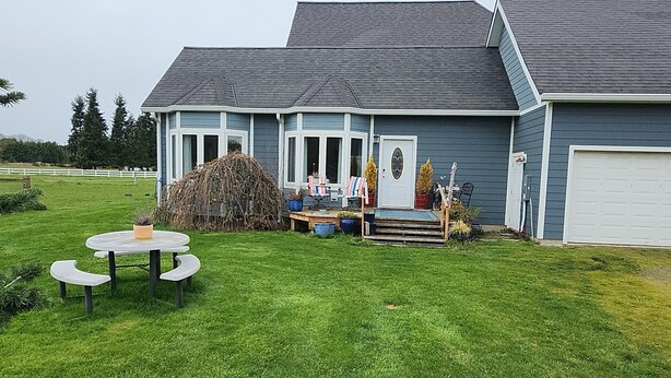 A house with a front yard, a garage, and a small patio with a table and chairs.