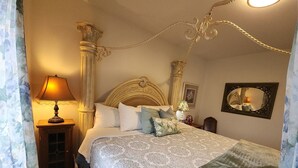 A bedroom with a bed, a nightstand, a lamp, a mirror, and a decorative ceiling.