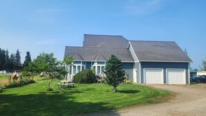 A two-story house with a sloped roof, a front porch, and a well-maintained lawn.
