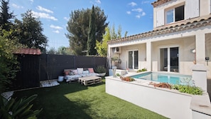 Ein zweistöckiges Haus mit Swimmingpool, einem eingezäunten Garten und einer Terrasse mit Gartenmöbeln.