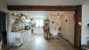 Une cuisine moderne avec des meubles blancs, un plafond avec poutre en bois et un îlot central.