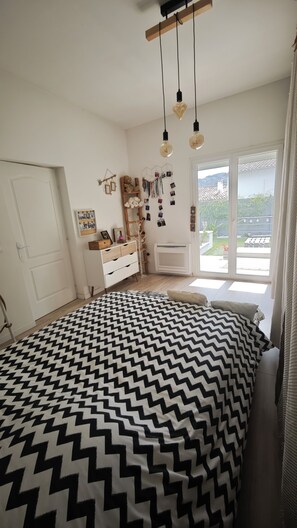 Une chambre à coucher avec un lit, une commode, des éléments décoratifs sur les murs et une vue par la fenêtre.