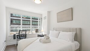 A hotel room with a large bed, a desk with a chair, a window with blinds, and a wall-mounted artwork. - Luxury DT Escape 3Bed2Bath! Pool |Gym |Parking (Toronto)