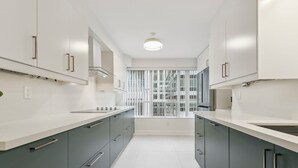 A modern kitchen with white countertops, grey cabinets, and a window with vertical blinds. - Luxury DT Escape 3Bed2Bath! Pool |Gym |Parking (Toronto)