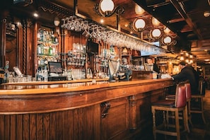 Un bar con paneles de madera, una variedad de botellas y un cantinero.