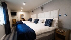 Una camera d'albergo con due letti, una televisione, uno specchio e un comodino.