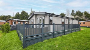 A mobile home with a fenced yard, a small garden, and a clear sky. - Host Stay Sandy Lane Lodge (York)