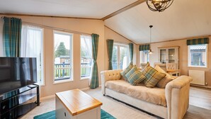 A spacious living room with a sofa, a TV, and a wooden coffee table. - Host Stay Sandy Lane Lodge (York)